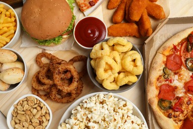 Photo of Pizza, chicken nuggets and other fast food on wooden table, flat lay