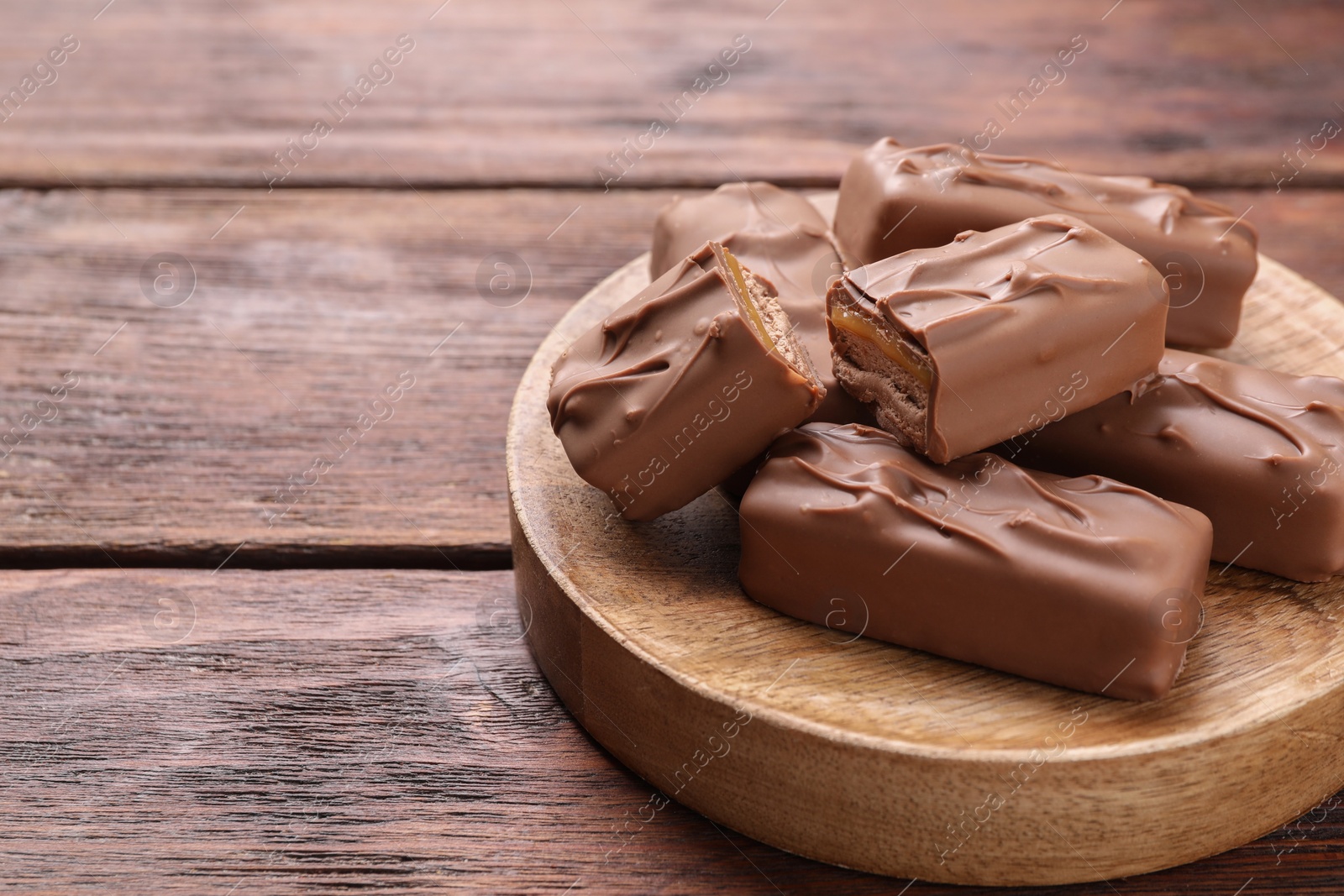 Photo of Tasty chocolate bars with nougat on wooden table, space for text