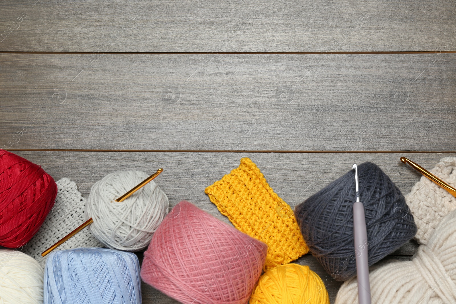 Photo of Clews, knitting and crochet hooks on wooden table, flat lay. Space for text