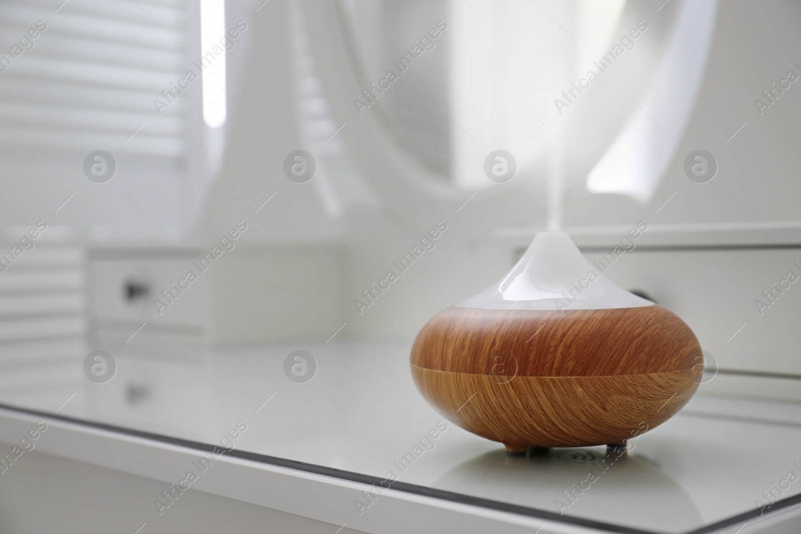 Photo of Essential oils diffuser on white table   in room. Space for text