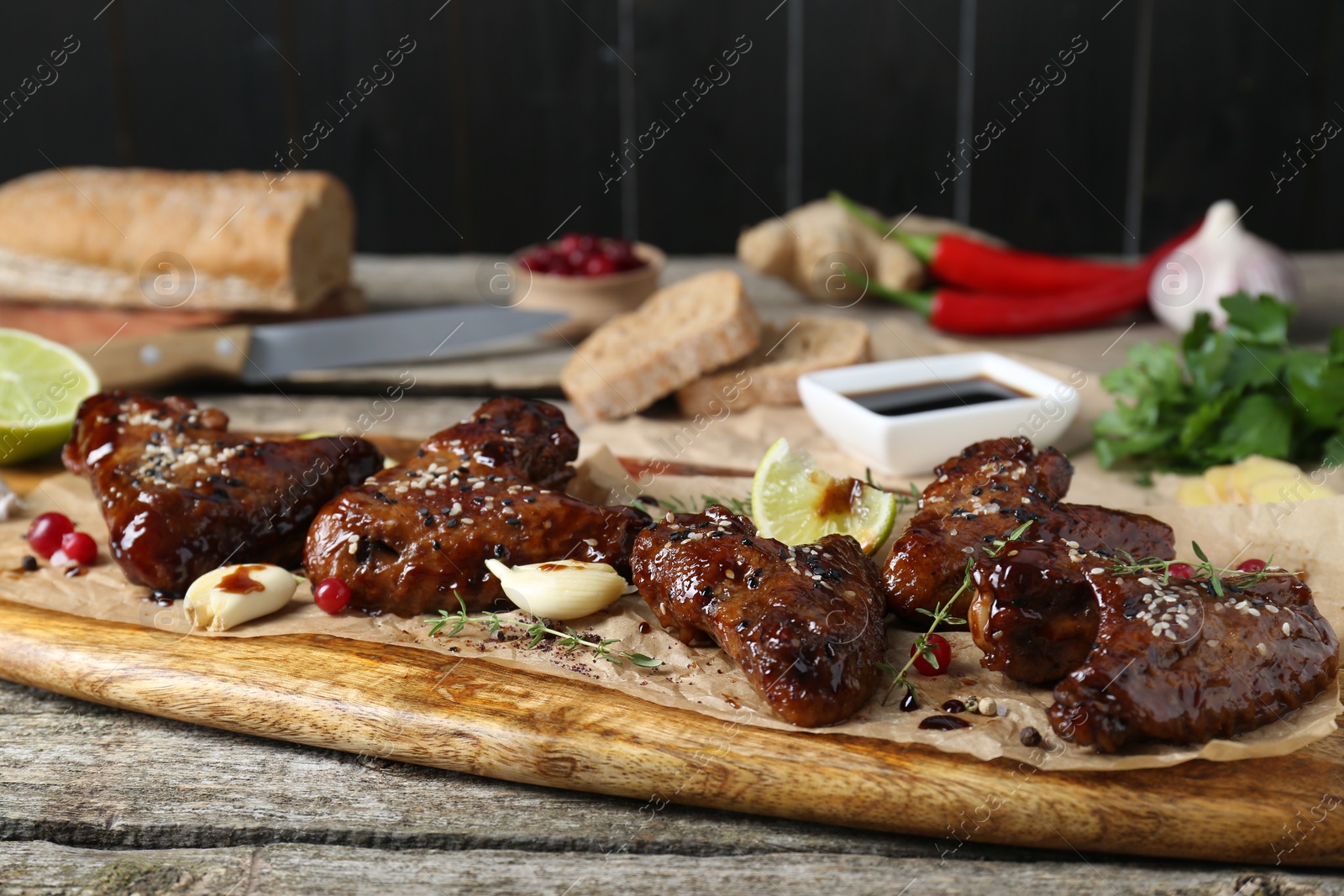 Photo of Tasty chicken wings glazed in soy sauce with garnish on wooden table