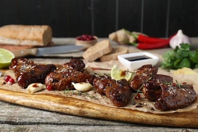Photo of Tasty chicken wings glazed in soy sauce with garnish on wooden table