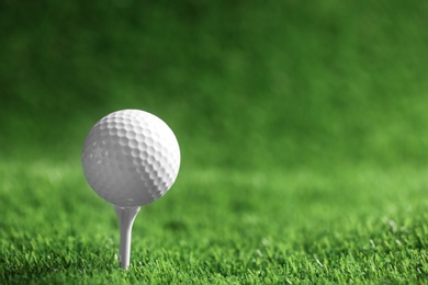 Photo of Golf ball with tee on artificial grass, space for text