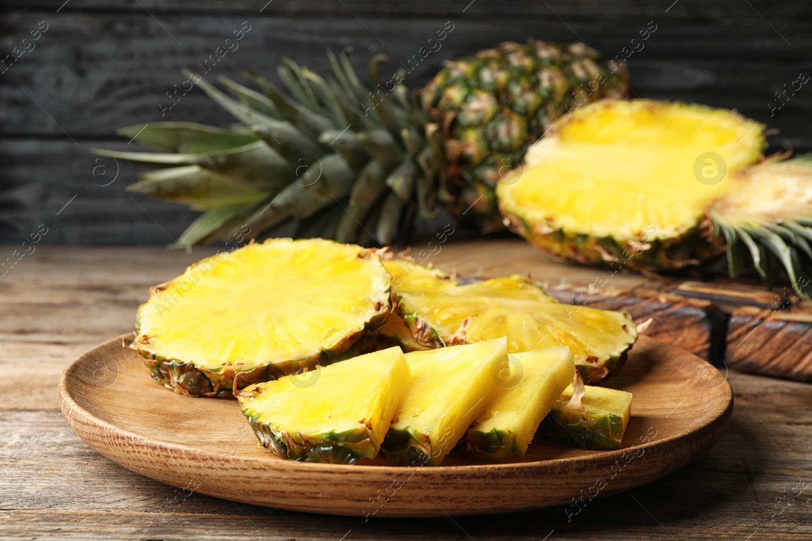 Photo of Tray with cut fresh juicy pineapple on wooden table