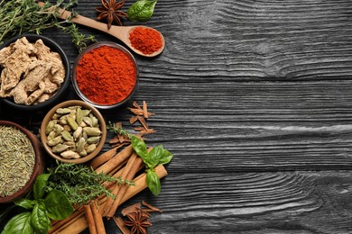 Photo of Different natural spices and herbs on black wooden table, flat lay. Space for text