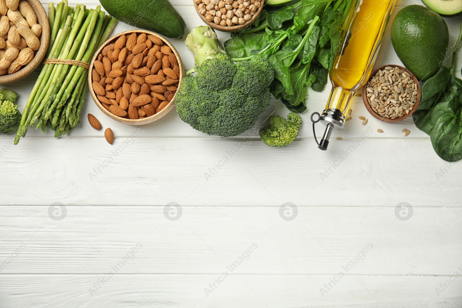 Photo of Different products rich in vitamin E on white wooden table, flat lay. Space for text