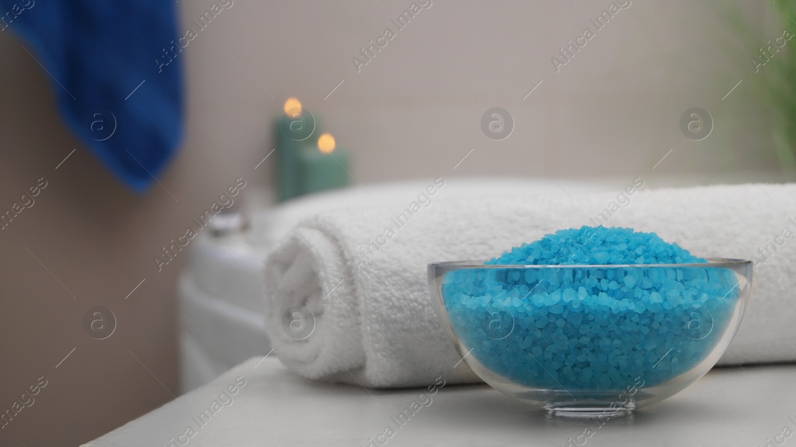 Photo of Bowl with bath salt and fluffy towel on table in bathroom. Space for text