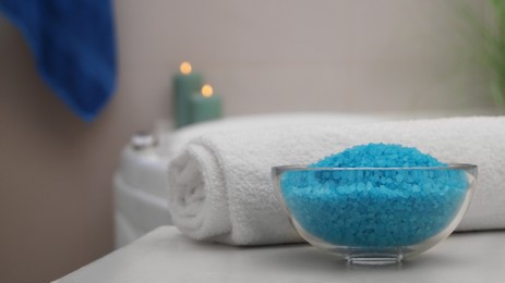 Photo of Bowl with bath salt and fluffy towel on table in bathroom. Space for text