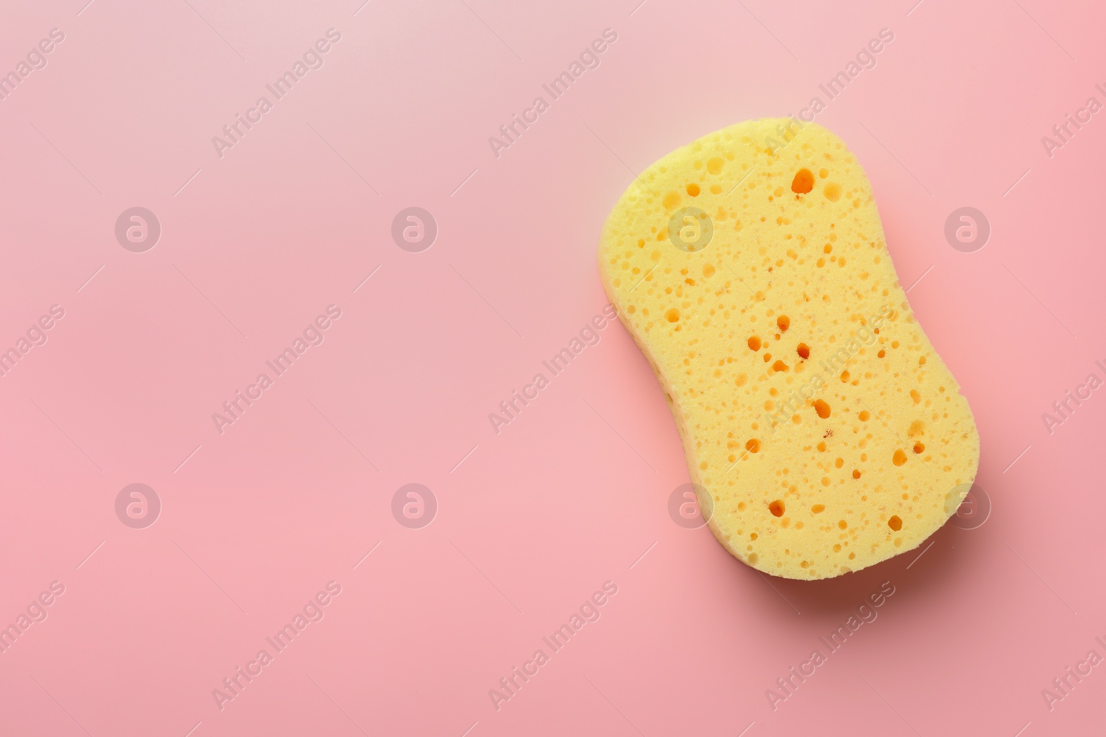 Photo of New yellow sponge on pink background, top view. Space for text