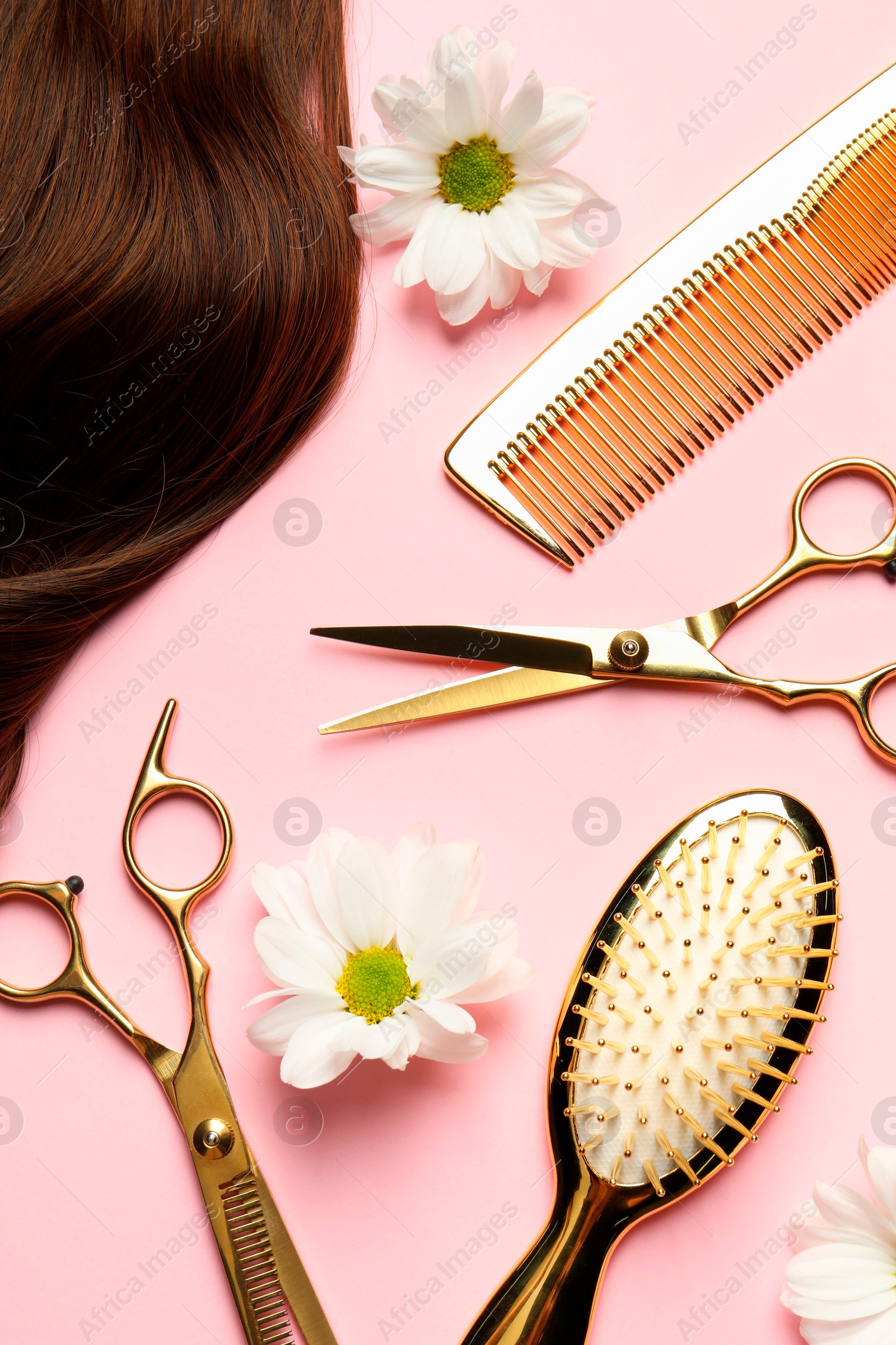 Photo of Flat lay composition with different hairdresser tools and flowers on pink background