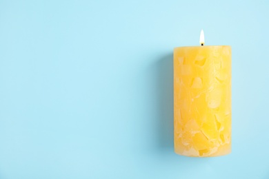 Photo of Alight wax candle and space for text on color background