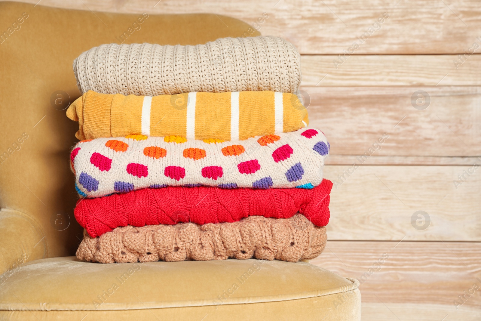 Photo of Stack of winter clothes against wooden background. Space for text