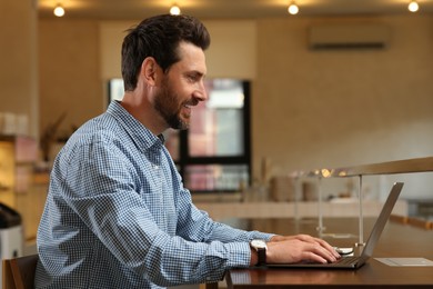 Photo of Man working on laptop at table in cafe