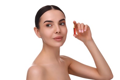 Beautiful young woman holding skincare ampoule on white background