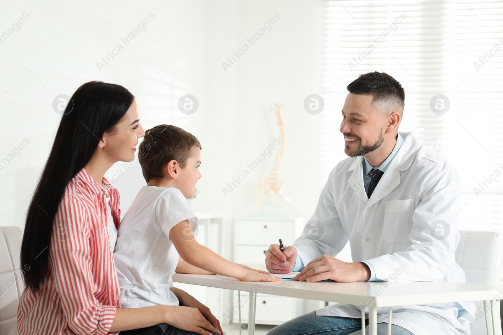 Photo of Little boy with mother visiting orthopedist at clinic