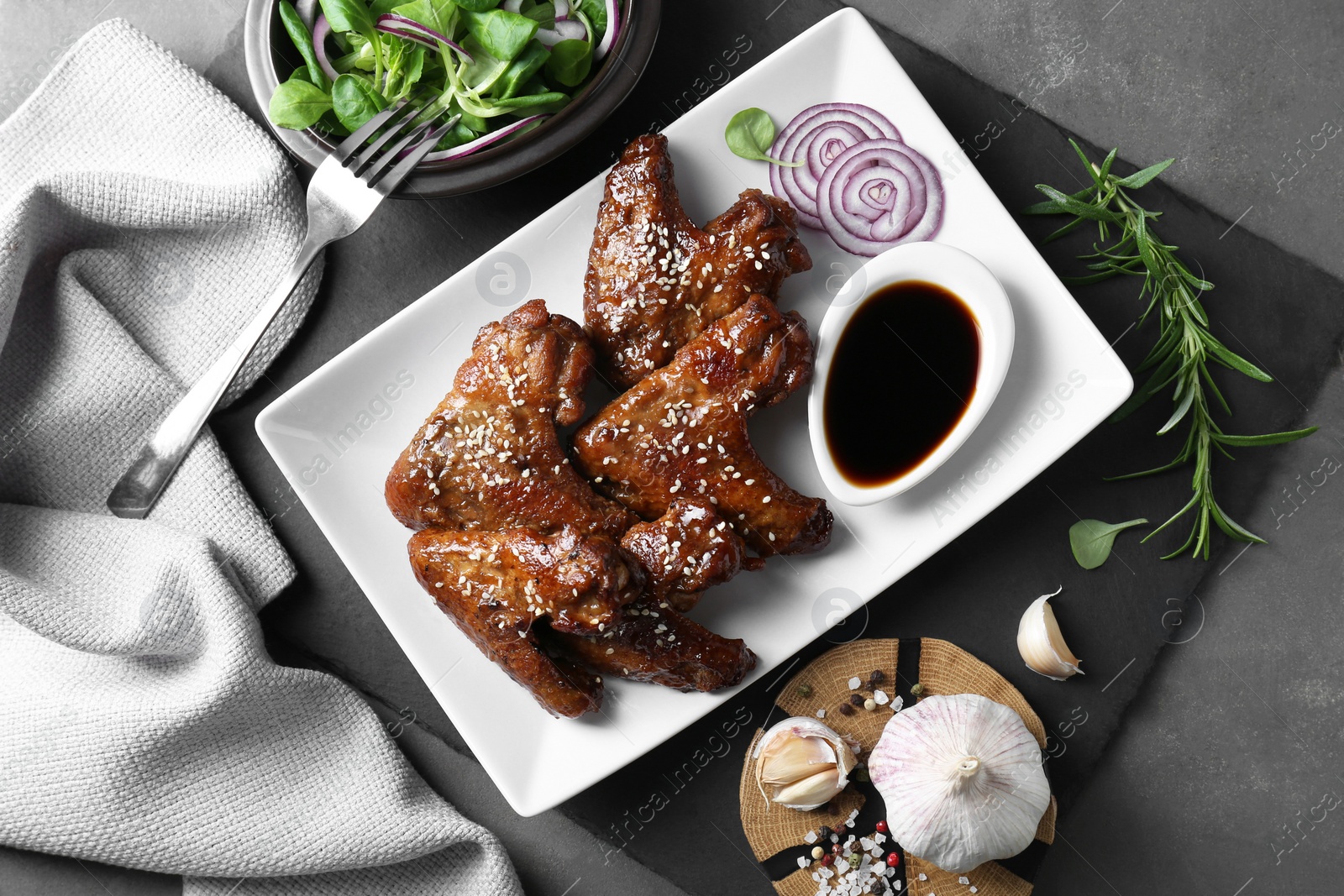 Photo of Chicken wings glazed with soy sauce served on grey table, flat lay