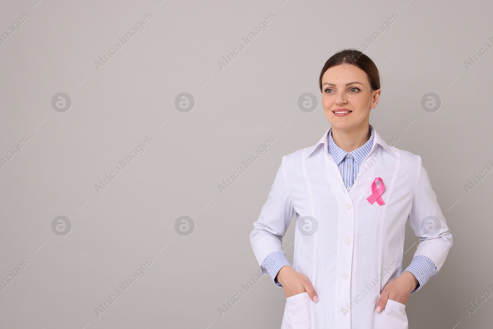 Photo of Mammologist with pink ribbon on grey background, space for text. Breast cancer awareness