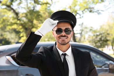 Young handsome driver standing near luxury car. Chauffeur service