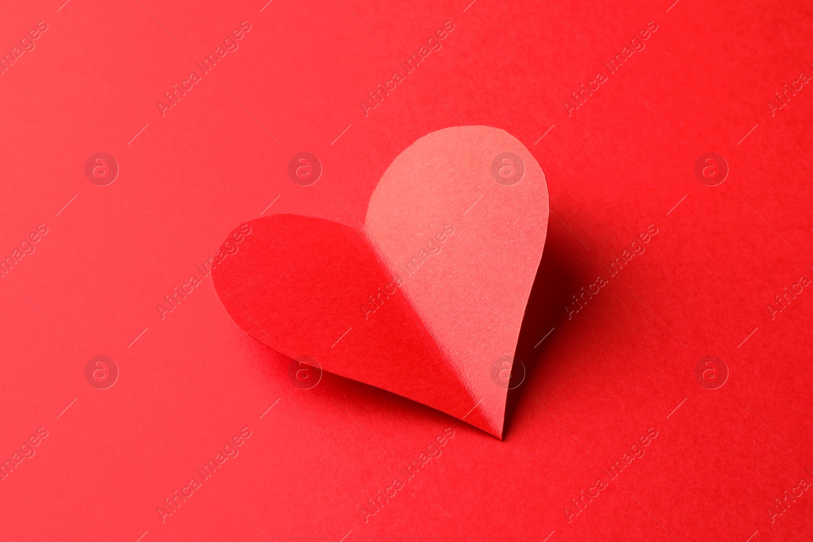 Photo of One bright paper heart on red background