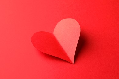 Photo of One bright paper heart on red background