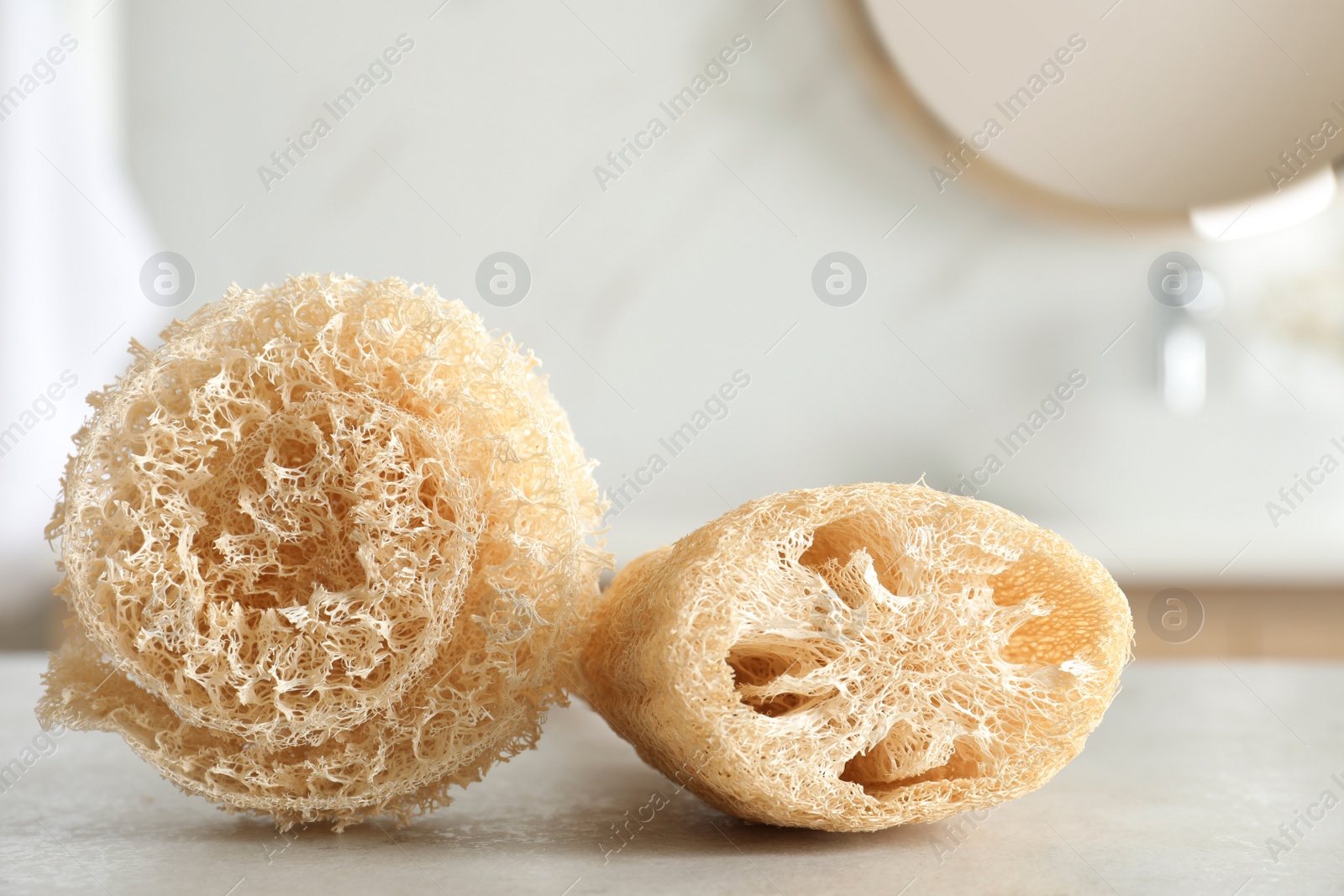 Photo of Natural loofah sponges on table in bathroom