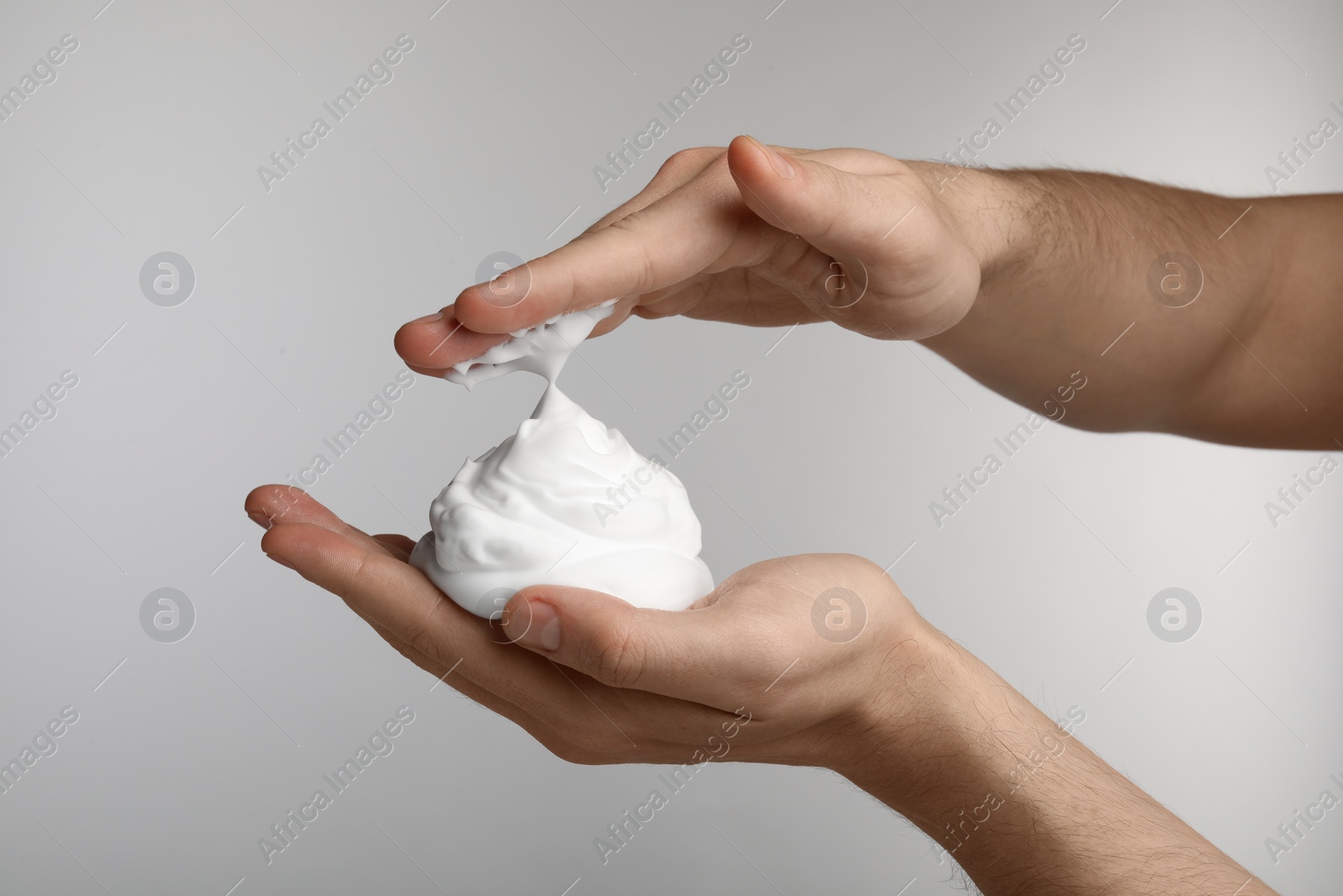 Photo of Man holding shaving foam on light grey background, closeup