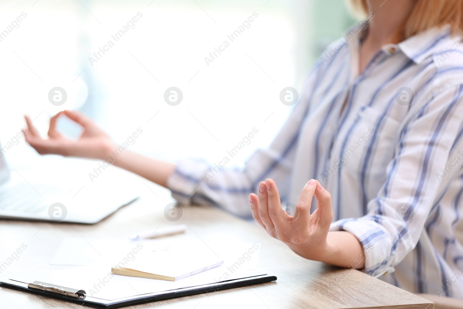 Photo of Beautiful woman meditating at table in office during break, closeup with space for text. Zen yoga