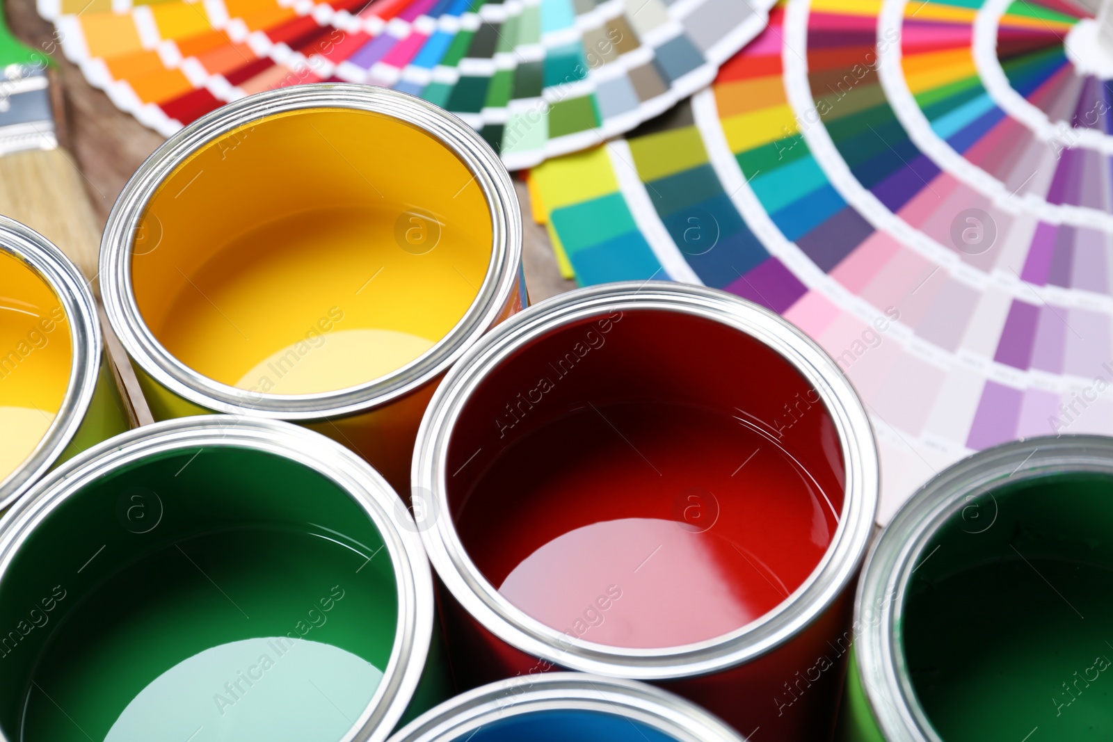 Photo of Paint cans and color palette samples on table, closeup