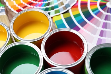 Paint cans and color palette samples on table, closeup