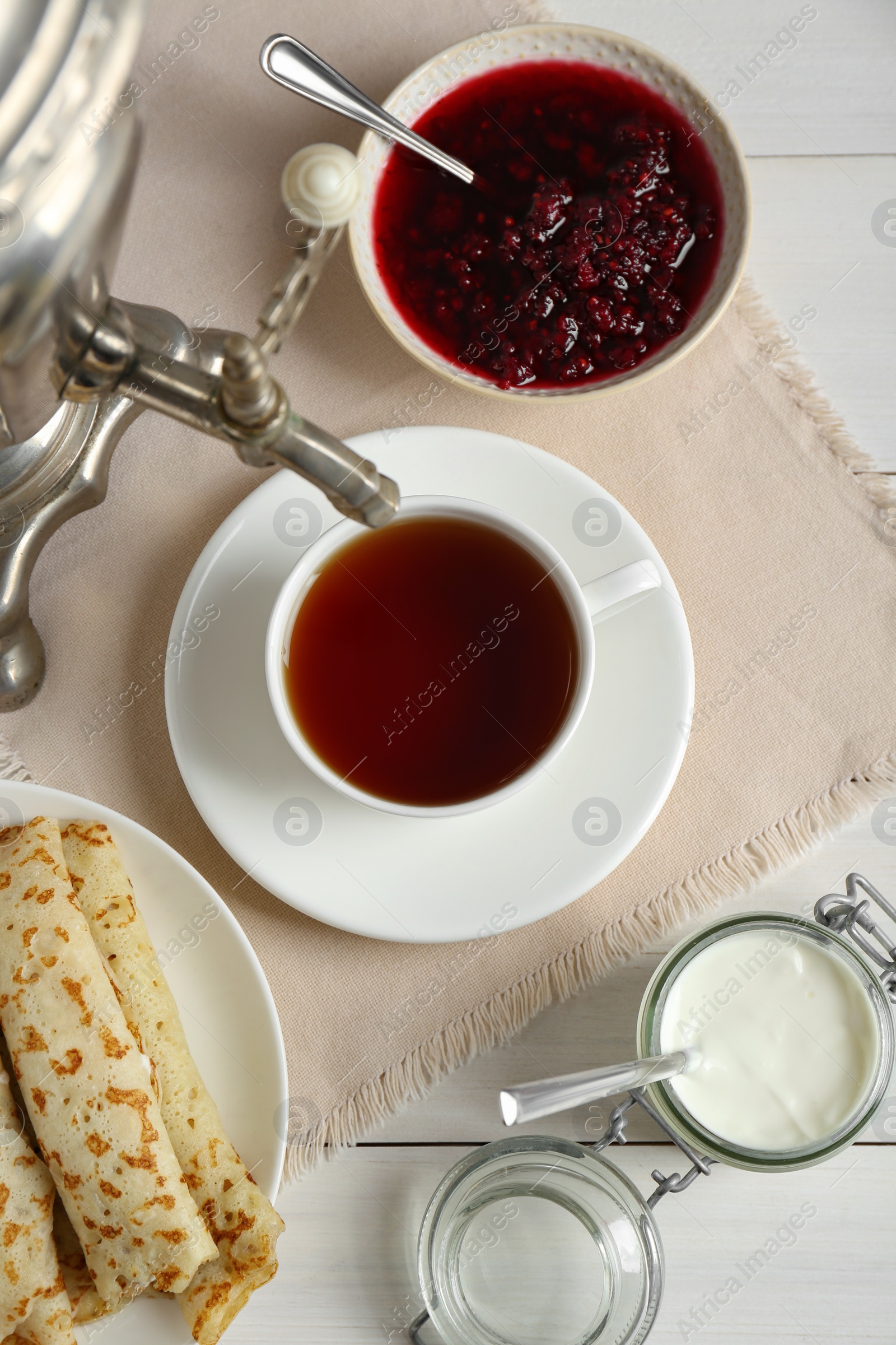 Photo of Vintage samovar, cup of hot drink and snacks served on white wooden table, flat lay. Traditional Russian tea ceremony