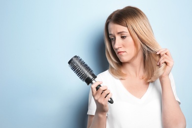 Young woman with hair loss problem on color background