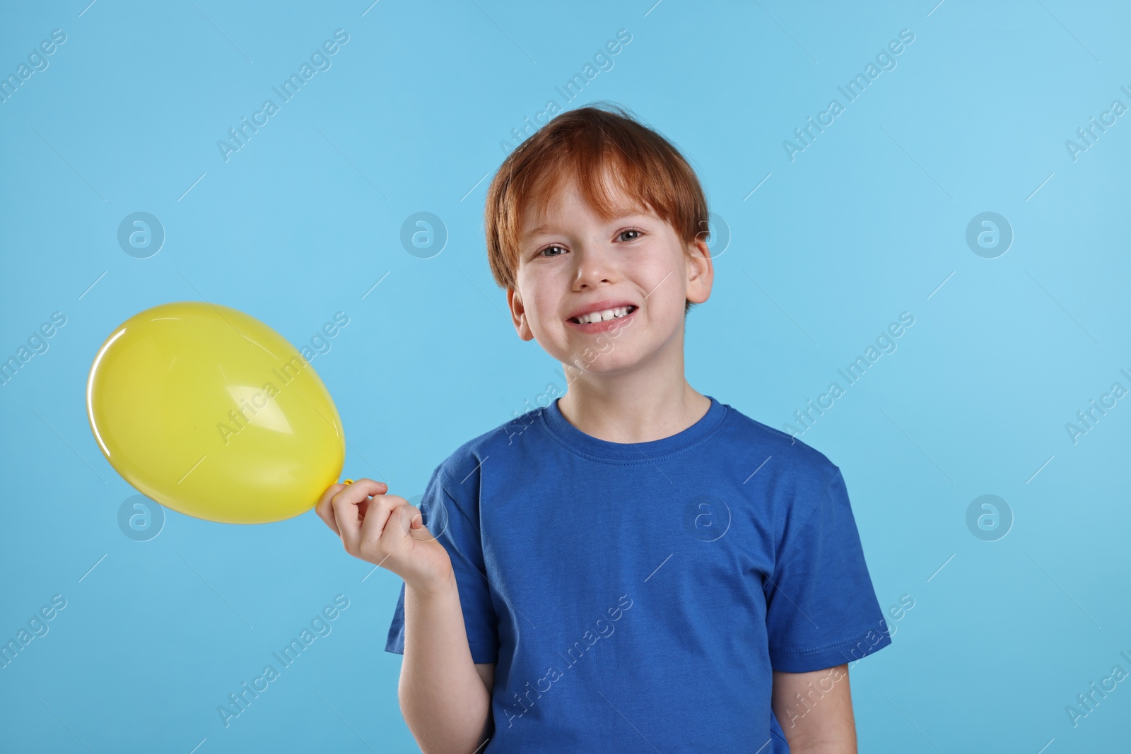 Photo of Boy with yellow balloon on light blue background