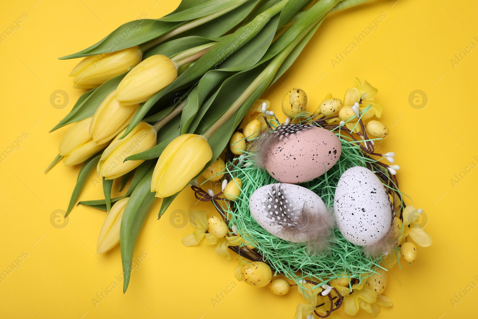 Photo of Flat lay composition with beautiful flowers and eggs on yellow background. Easter celebration