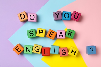 Photo of Cubes with question Do You Speak English on color background, flat lay