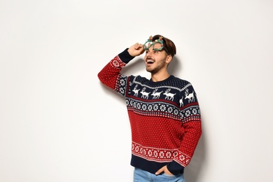 Photo of Young man in Christmas sweater with party glasses on white background