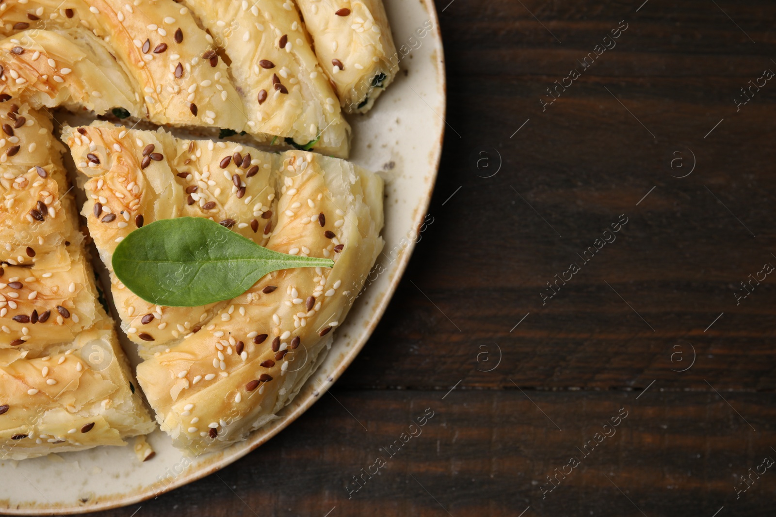 Photo of Delicious puff pastry with spinach on wooden table, top view. Space for text