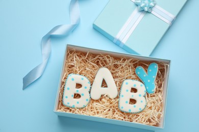 Photo of Baby shower cookies in gift box on turquoise background, flat lay