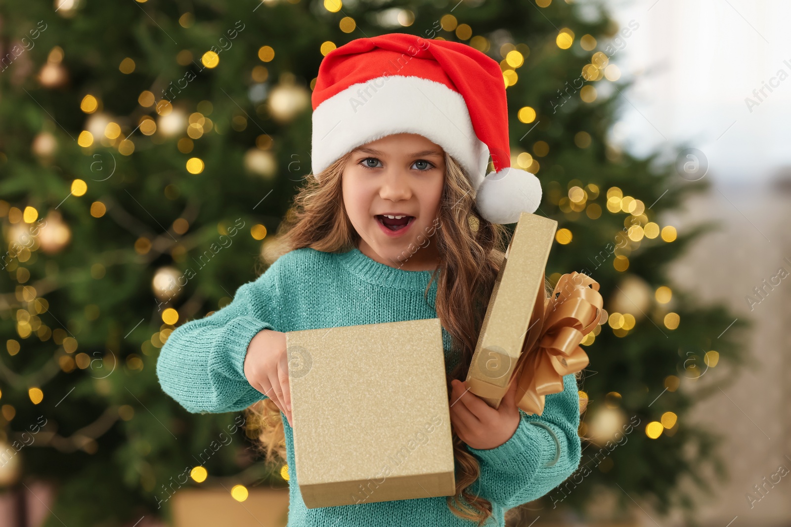 Photo of Emotional little girl opening Christmas gift at home