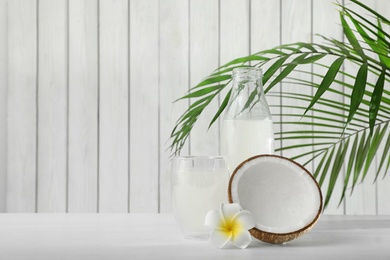 Photo of Composition with bottle and glass of coconut water on white wooden table. Space for text