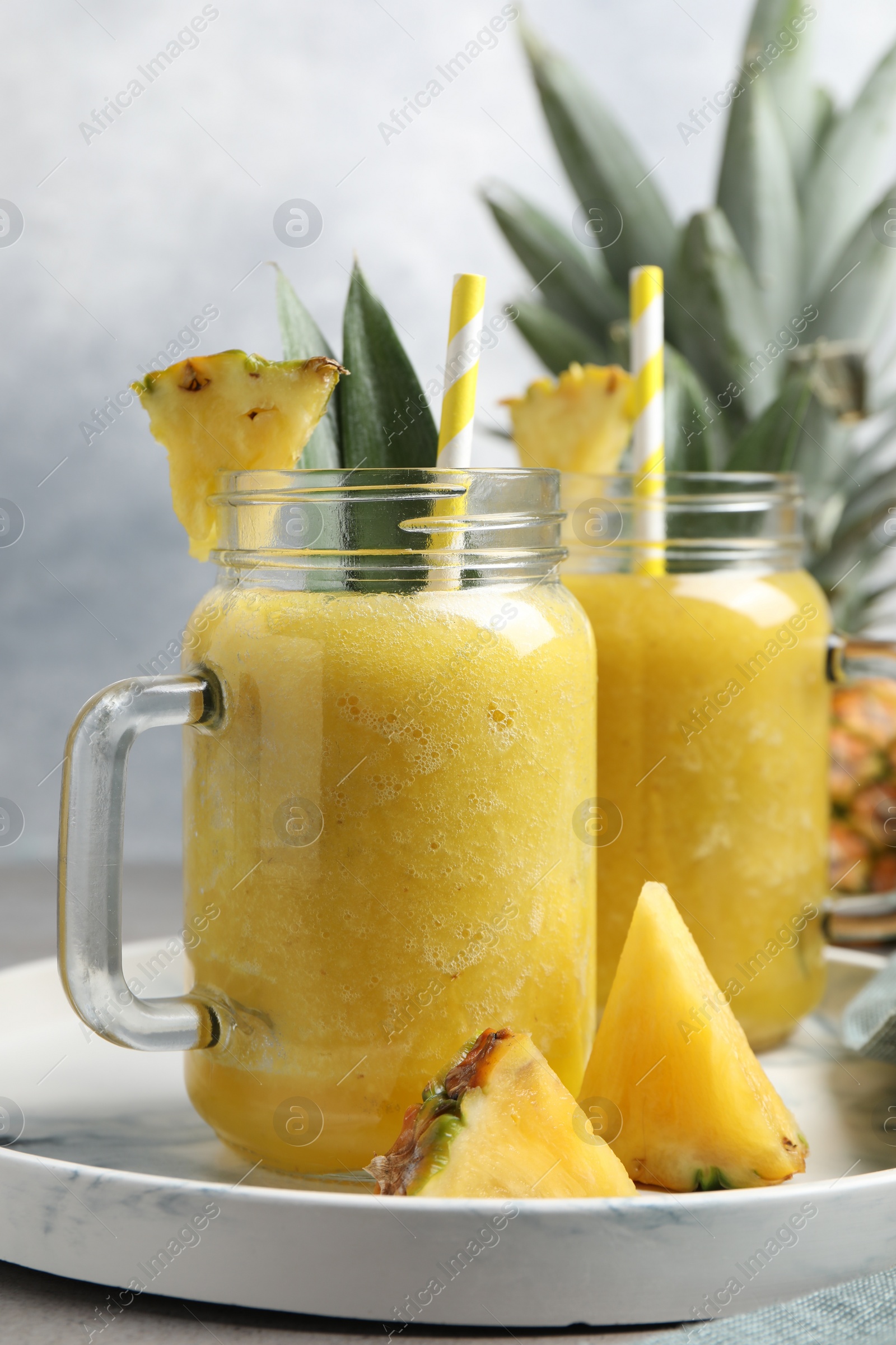 Photo of Tray with tasty pineapple smoothie and sliced fruit on table, closeup