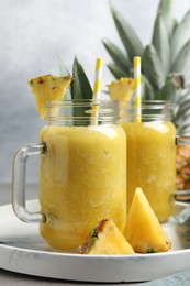 Photo of Tray with tasty pineapple smoothie and sliced fruit on table, closeup
