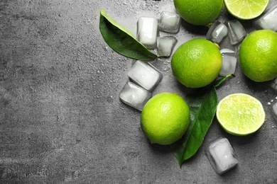 Photo of Composition with fresh ripe limes and ice cubes on gray background, top view