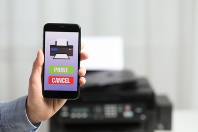 Photo of Man using printer management application on mobile phone in office, closeup and space for text