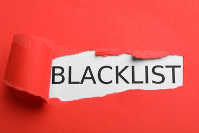 Photo of Word Blacklist on white background through hole in red paper, top view