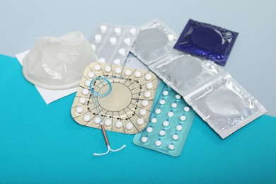 Photo of Contraceptive pills, condoms and intrauterine device on color background. Choice of birth control method