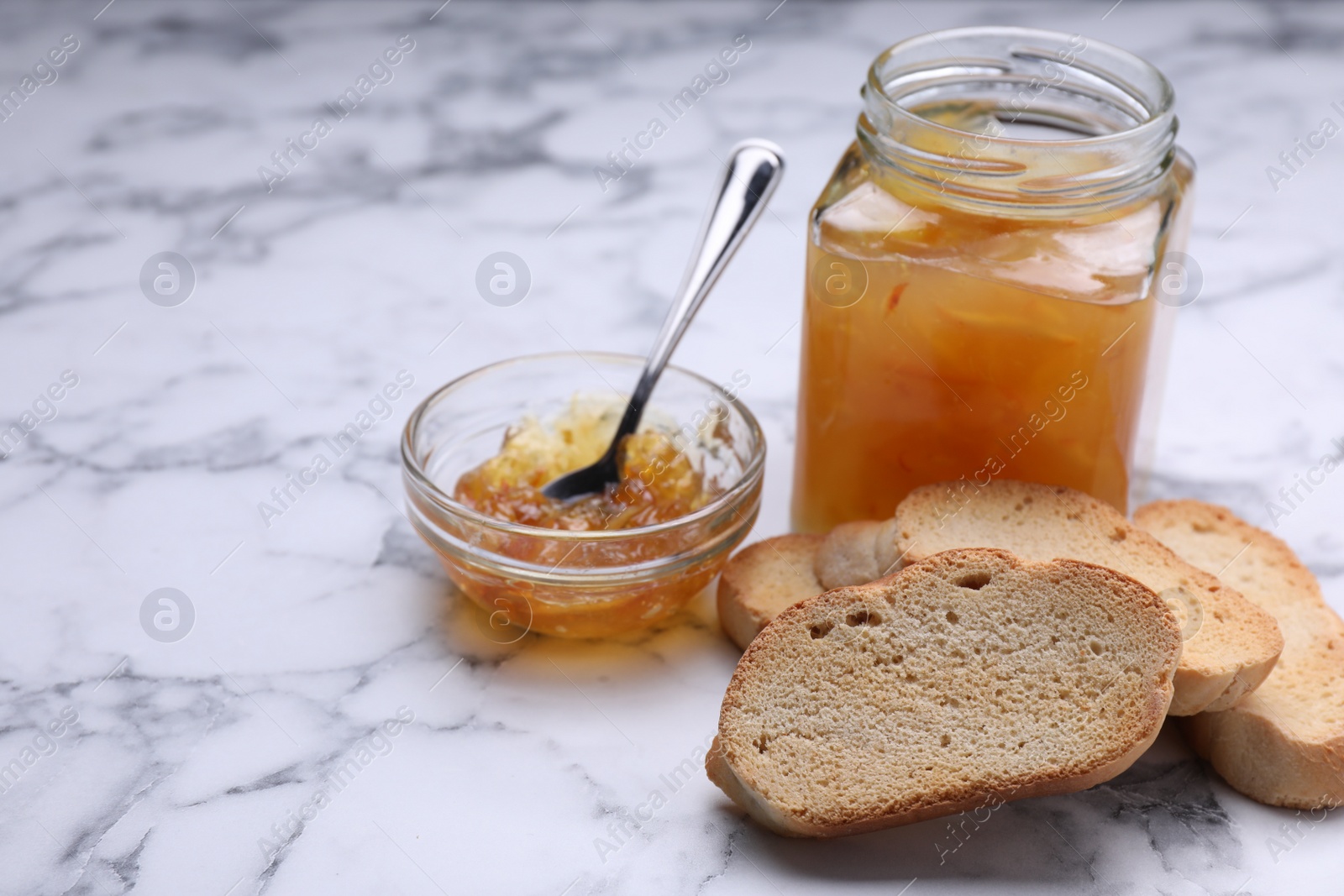 Photo of Hard chuck crackers and jam on white marble table. Space for text