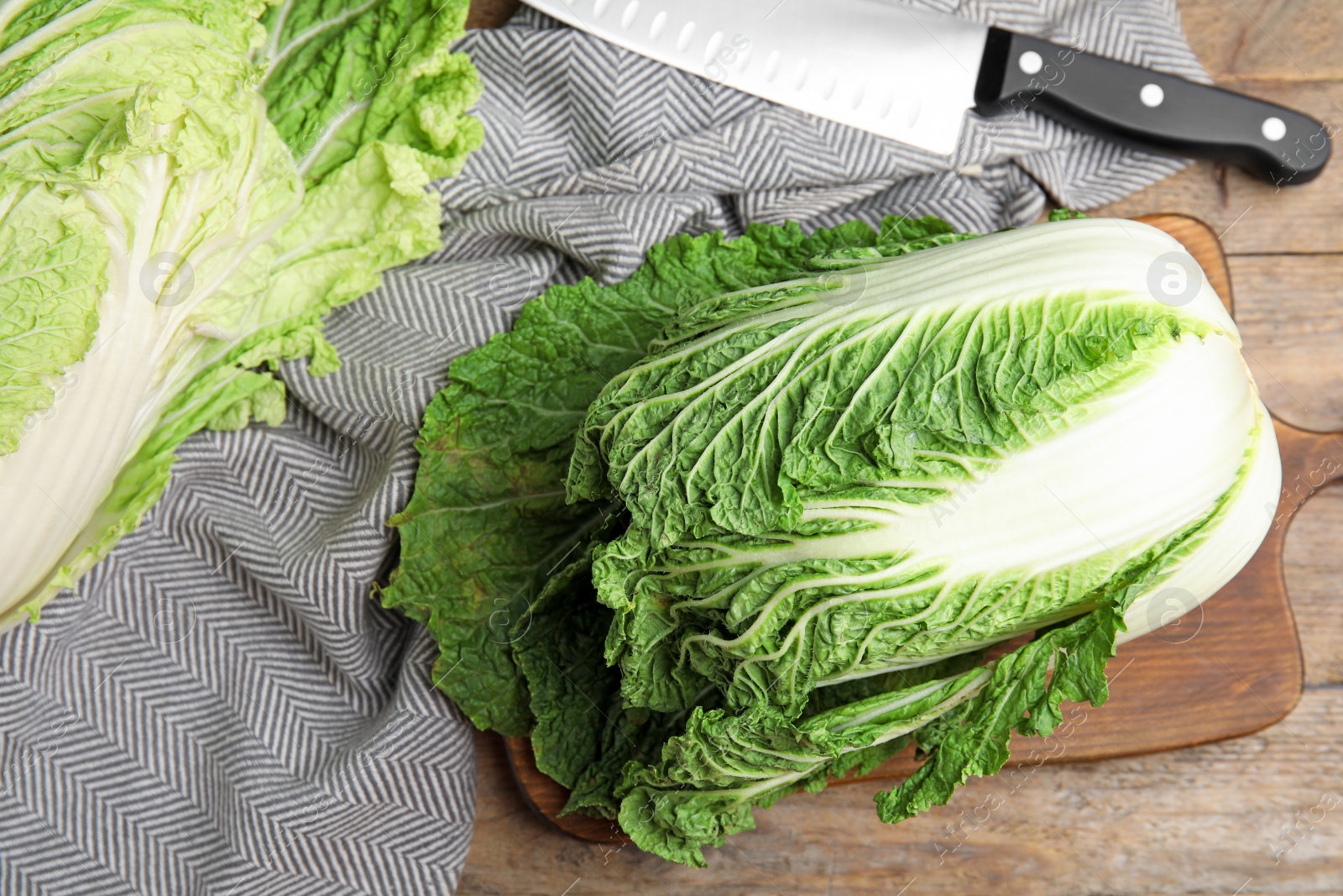 Photo of Fresh ripe Chinese cabbages and knife on wooden table, flat lay