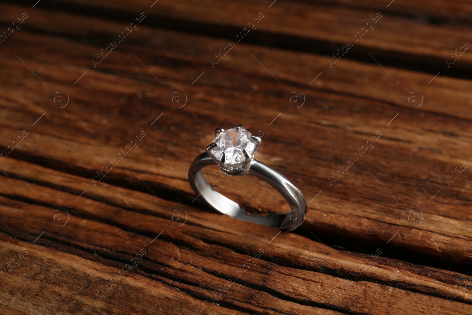 Photo of Beautiful luxury engagement ring with gemstone on wooden background, closeup