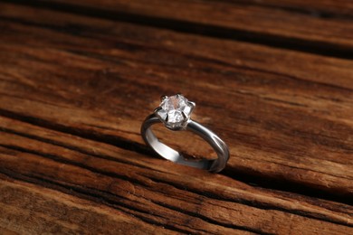 Photo of Beautiful luxury engagement ring with gemstone on wooden background, closeup