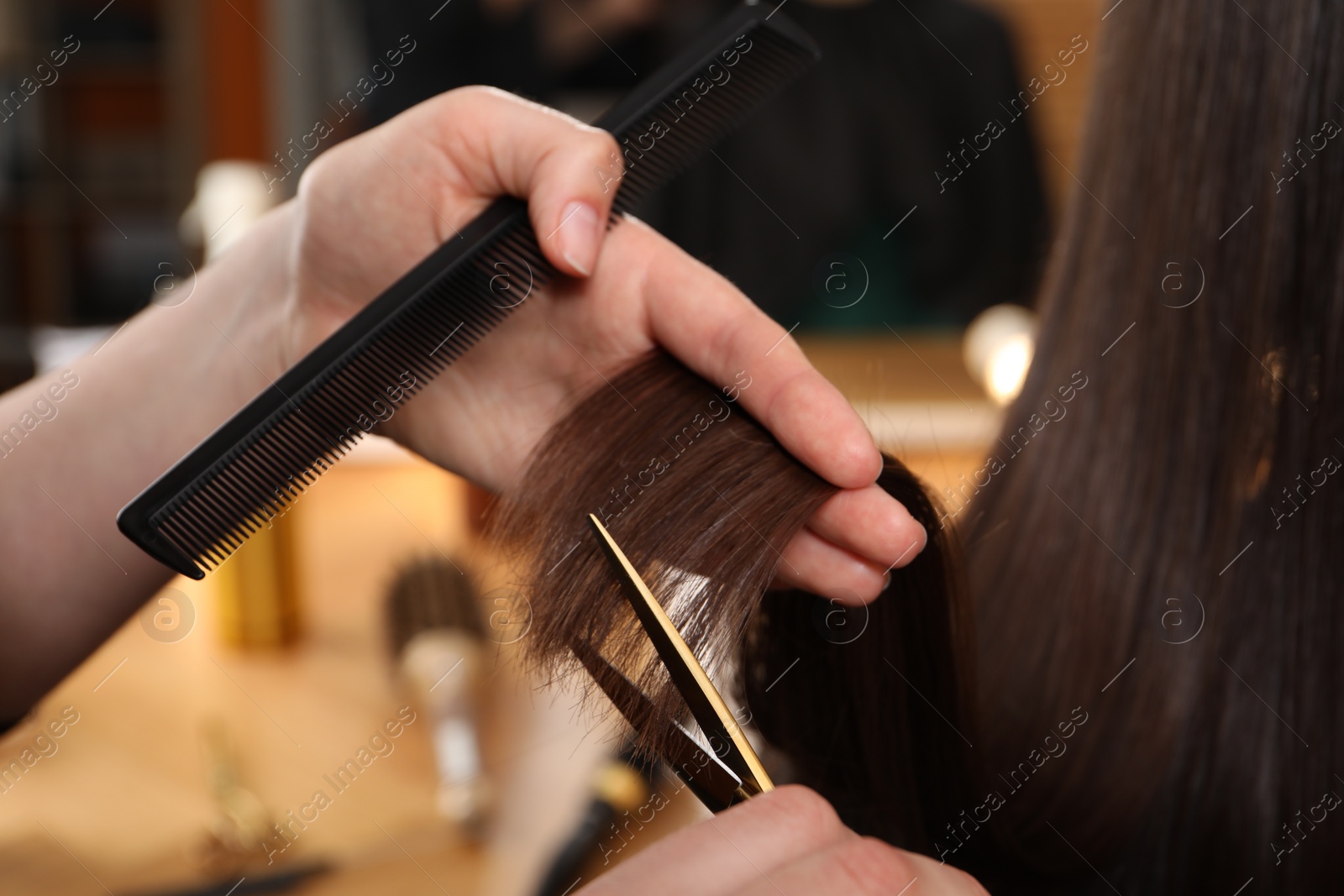 Photo of Hairdresser cutting client's hair with scissors in salon, closeup